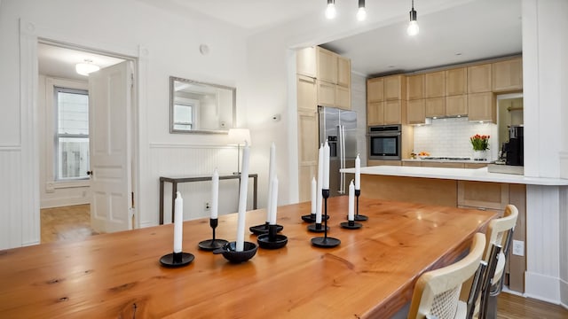 kitchen featuring a peninsula, light countertops, appliances with stainless steel finishes, decorative light fixtures, and backsplash