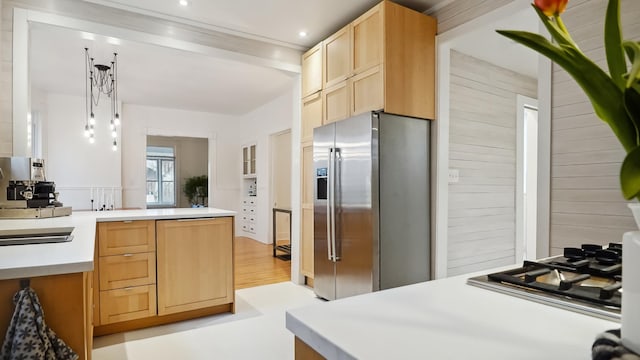 kitchen with light brown cabinetry, light countertops, appliances with stainless steel finishes, a peninsula, and light wood-style floors