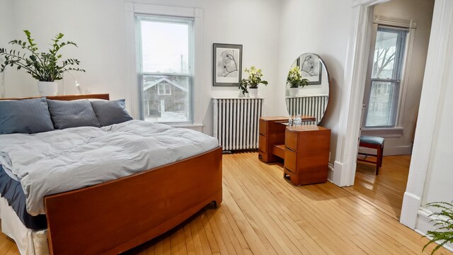 bedroom featuring light wood-style floors, multiple windows, and radiator