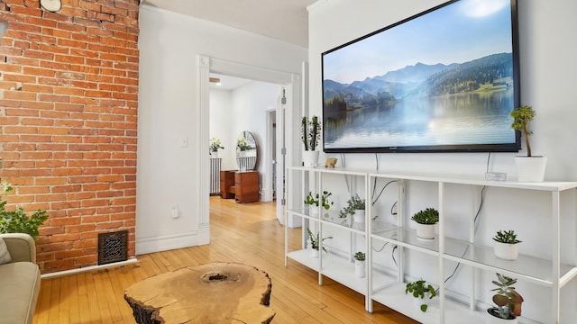 hall featuring visible vents, wood-type flooring, baseboards, and brick wall