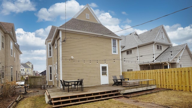 rear view of house featuring a deck, a fenced backyard, and roof with shingles