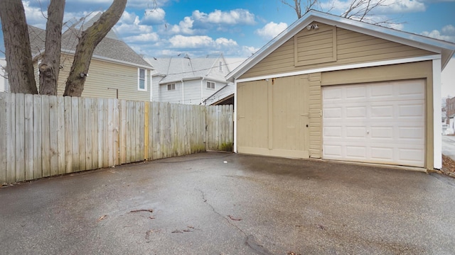 detached garage with aphalt driveway and fence