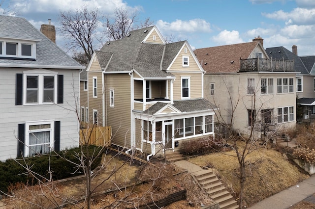 view of front facade featuring a shingled roof and a sunroom