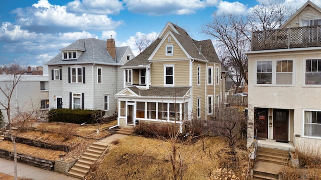 view of front of home featuring a sunroom and a chimney