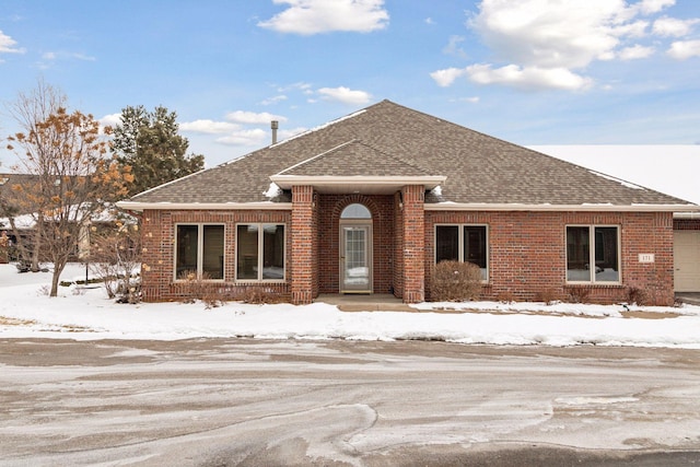 ranch-style home featuring a shingled roof and brick siding