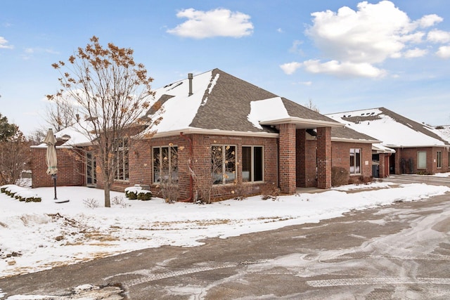 view of front of home featuring a shingled roof and brick siding