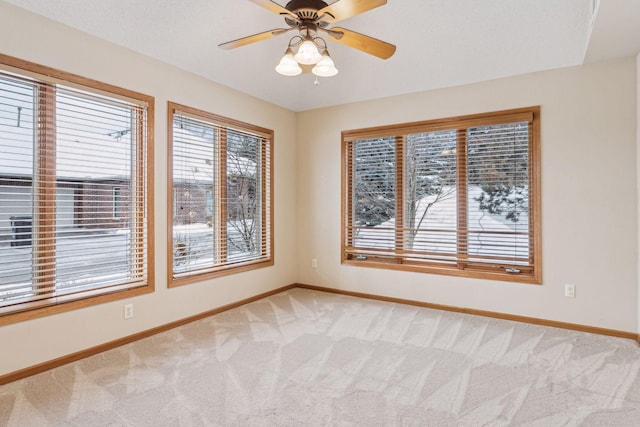 unfurnished room featuring light colored carpet, ceiling fan, and baseboards