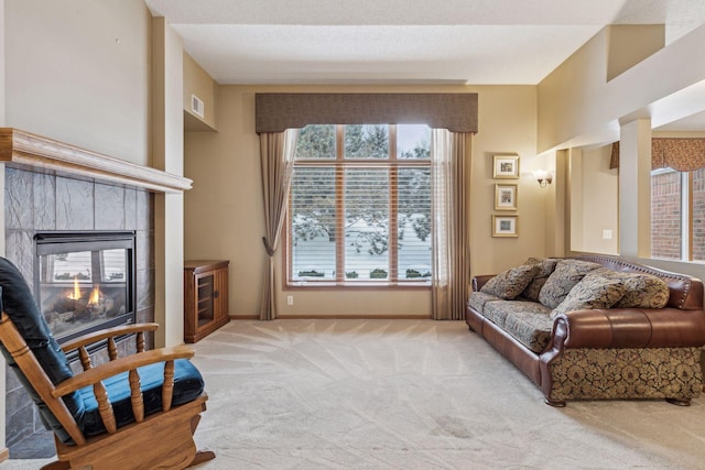 living area featuring baseboards, visible vents, a tiled fireplace, and light colored carpet