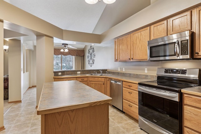 kitchen featuring lofted ceiling, appliances with stainless steel finishes, a center island, a sink, and light tile patterned flooring