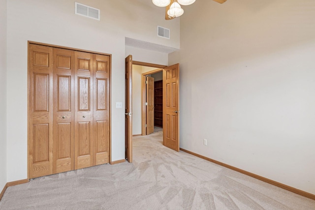 unfurnished bedroom featuring baseboards, visible vents, a closet, and light colored carpet