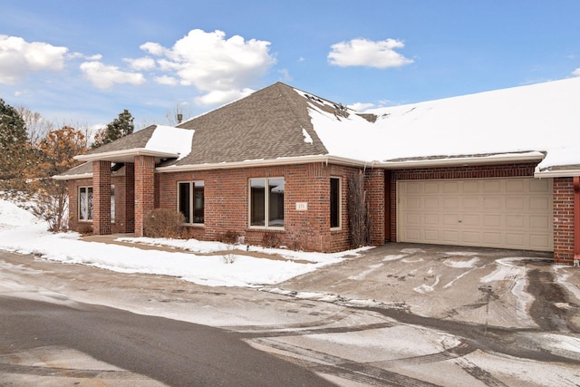 view of front of home featuring a garage, driveway, brick siding, and a shingled roof