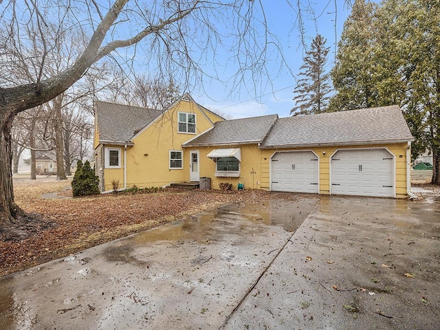 230 Mcleod Ave W, Winsted, MN 55395 - view of front facade featuring an attached garage, concrete driveway, a shingled roof, and stucco siding
