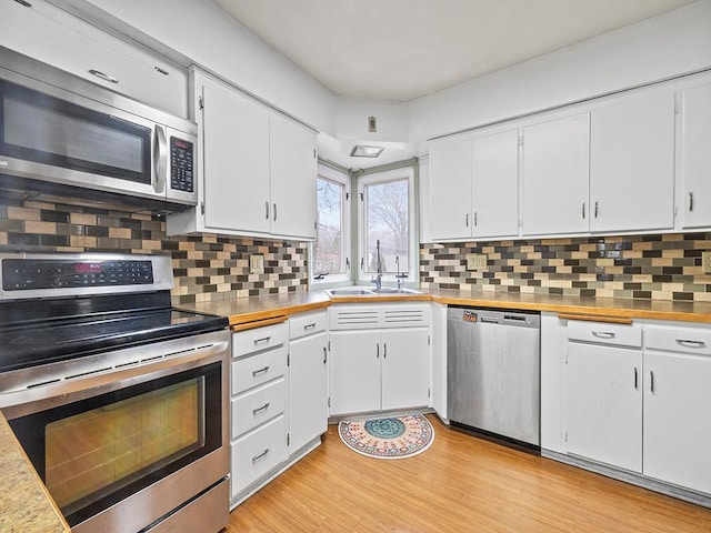 230 Mcleod Ave W, Winsted, MN 55395 - kitchen with appliances with stainless steel finishes, a sink, white cabinets, light wood-style floors, and backsplash