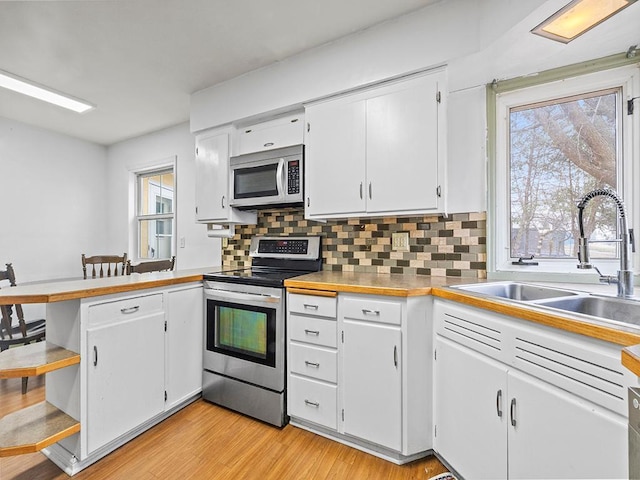 230 Mcleod Ave W, Winsted, MN 55395 - kitchen featuring stainless steel appliances, a sink, white cabinets, a peninsula, and tasteful backsplash