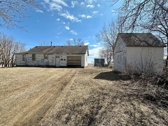 back of house with an outdoor structure, stone siding, and a storage shed