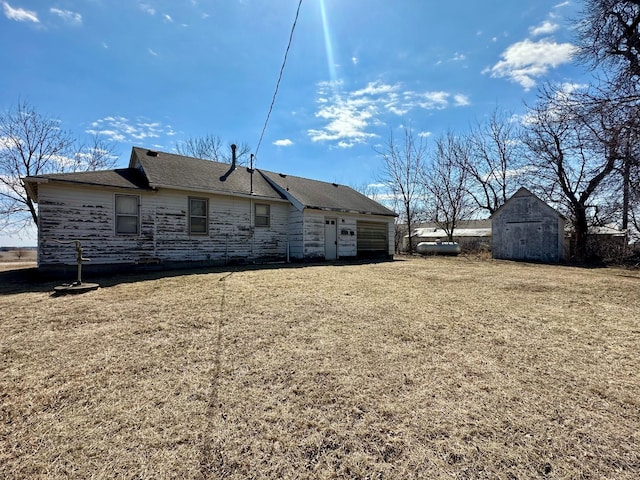 rear view of property with an outdoor structure, a storage unit, and a lawn