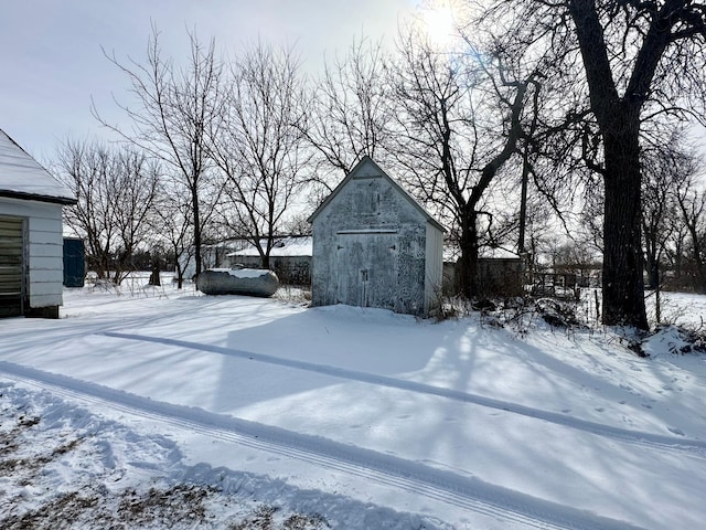 yard covered in snow featuring a shed and an outbuilding