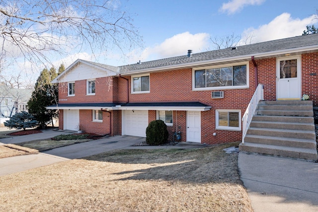 townhome / multi-family property with a garage, concrete driveway, brick siding, and roof with shingles