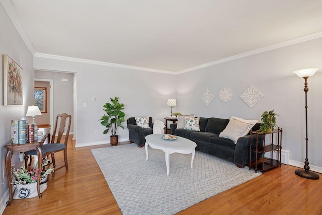 living area featuring ornamental molding, baseboards, and light wood finished floors