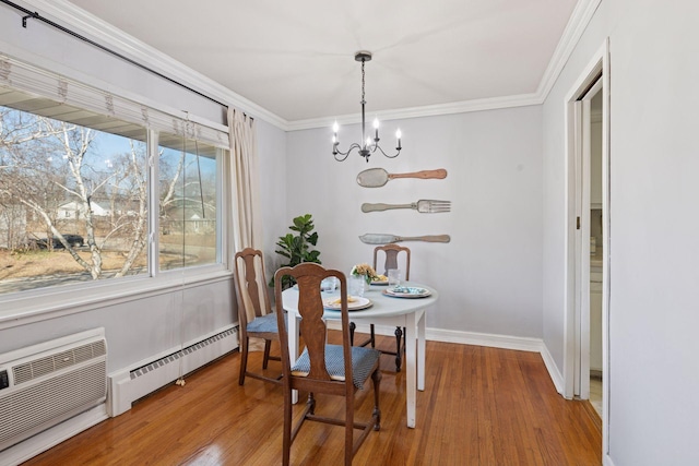 dining area with an inviting chandelier, a baseboard radiator, crown molding, and wood finished floors