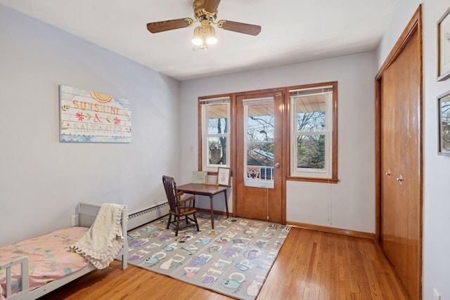 bedroom featuring a closet, ceiling fan, light wood finished floors, and baseboard heating