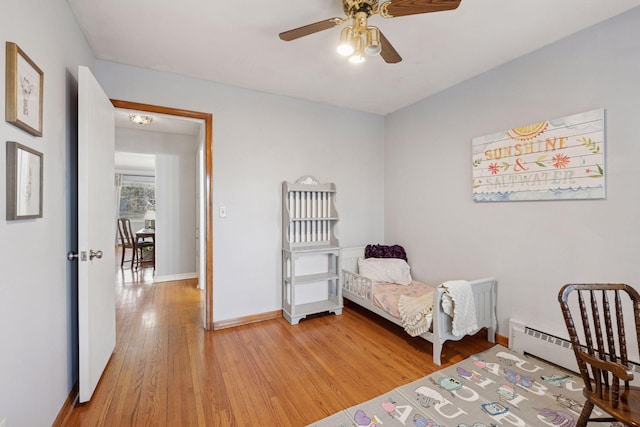 bedroom featuring baseboard heating, baseboards, ceiling fan, and light wood finished floors