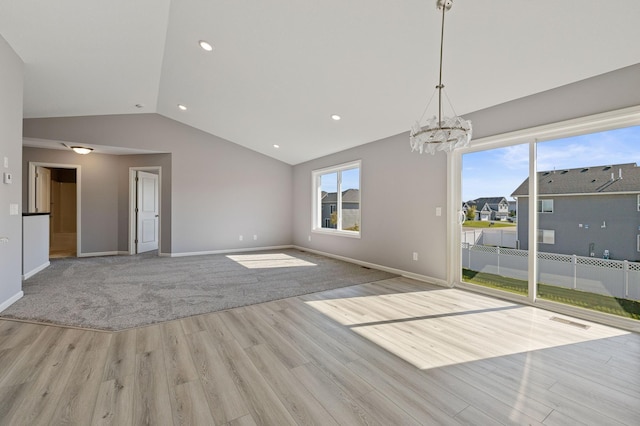 unfurnished living room with lofted ceiling, a notable chandelier, and light wood-type flooring