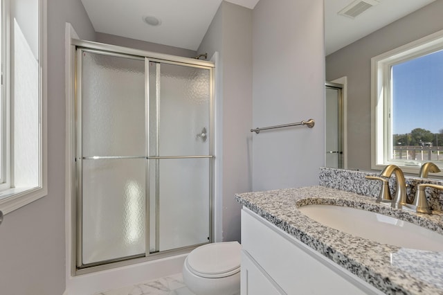 bathroom with vanity, a shower with door, and toilet