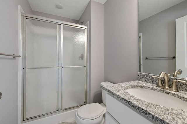 bathroom with vanity, a shower with door, and toilet