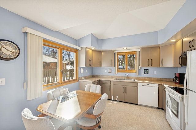 kitchen featuring white appliances, vaulted ceiling, light countertops, and a sink