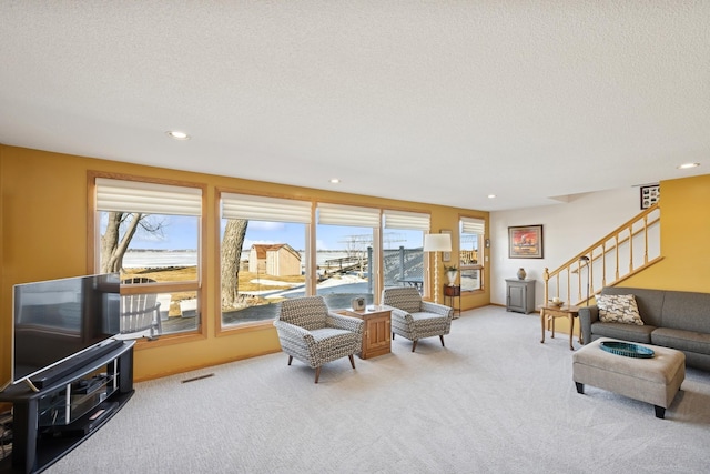 carpeted living room with a textured ceiling, stairway, visible vents, and recessed lighting