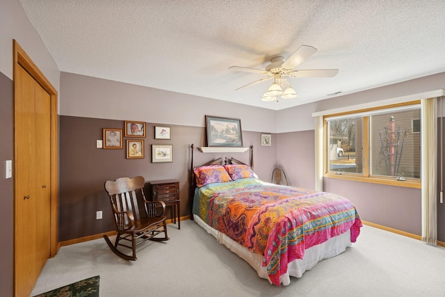 bedroom with baseboards, a closet, a textured ceiling, and light colored carpet