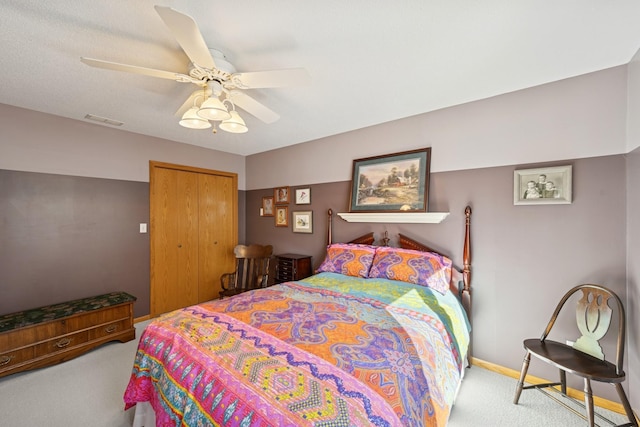 carpeted bedroom with ceiling fan, a closet, visible vents, and baseboards