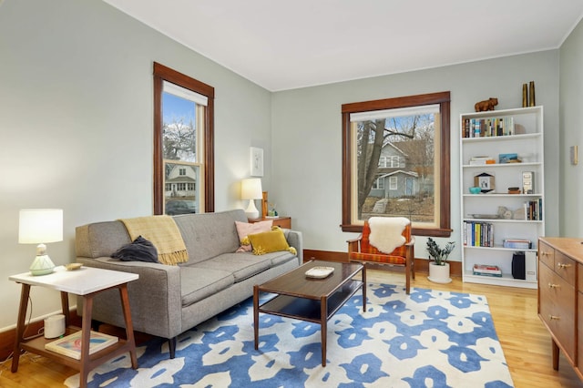 living area featuring baseboards, light wood-style flooring, and a healthy amount of sunlight