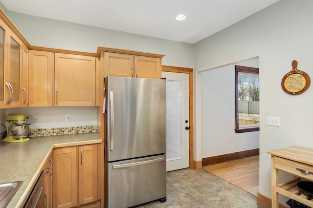 kitchen with baseboards, glass insert cabinets, freestanding refrigerator, light countertops, and recessed lighting