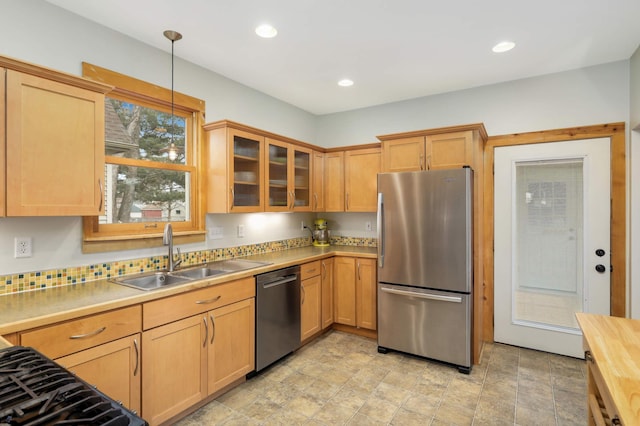 kitchen with decorative light fixtures, recessed lighting, stainless steel appliances, a sink, and glass insert cabinets