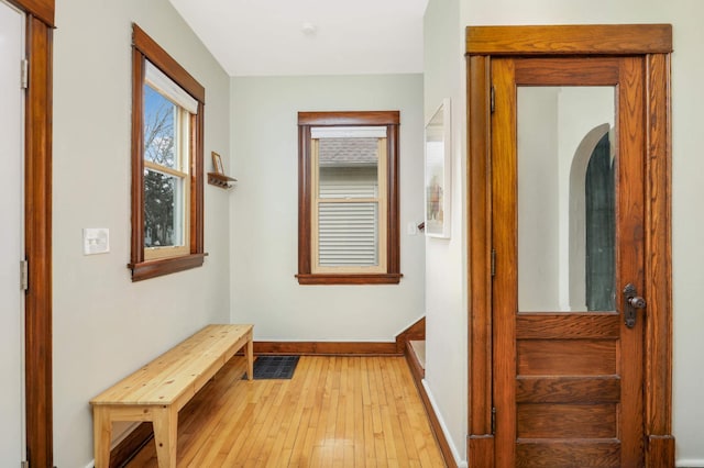 hallway featuring visible vents, light wood-style flooring, and baseboards