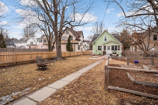 view of yard featuring a fire pit, a fenced backyard, and a residential view