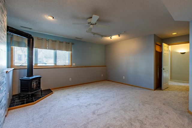 empty room with a wood stove, carpet flooring, ceiling fan, baseboards, and recessed lighting