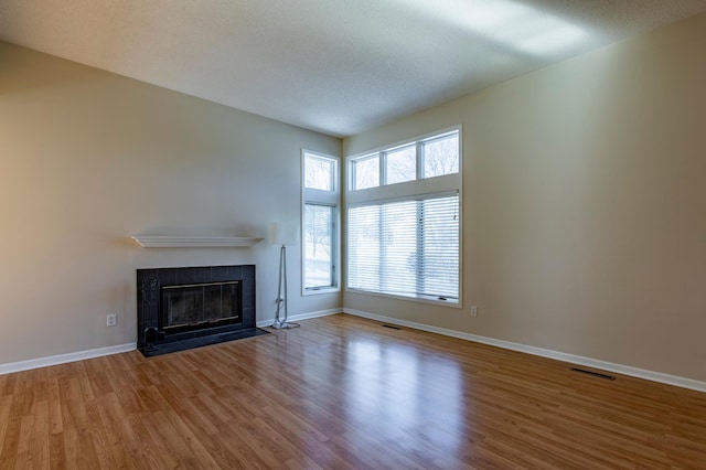 unfurnished living room with wood finished floors, a fireplace, and baseboards