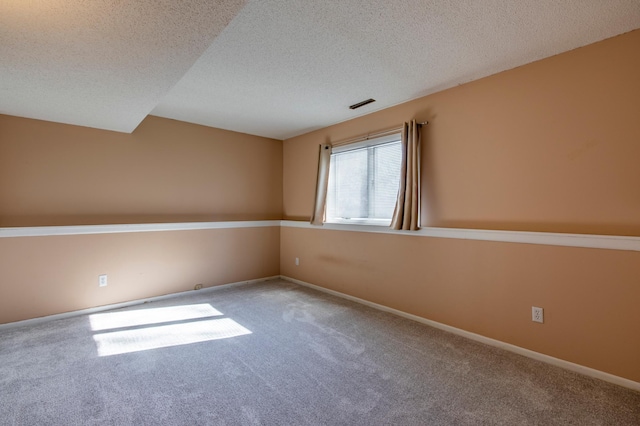 carpeted empty room featuring a textured ceiling and baseboards