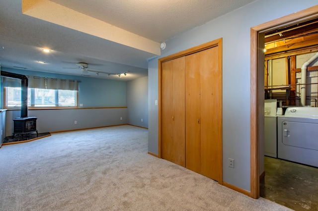 602 Cortland Ln SW, Rochester, MN 55902 - unfurnished living room featuring independent washer and dryer, a wood stove, ceiling fan, carpet, and a textured ceiling
