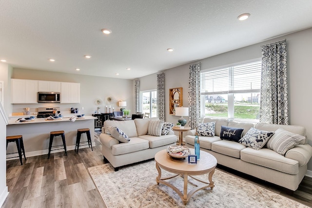 living room with recessed lighting, a textured ceiling, baseboards, and wood finished floors