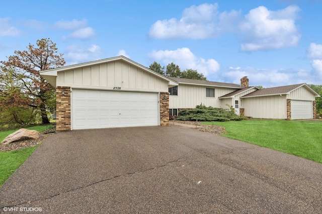 2528 Birchview Ln, Minnetonka, MN 55305 - view of front facade featuring driveway, brick siding, a front lawn, a garage, and a chimney