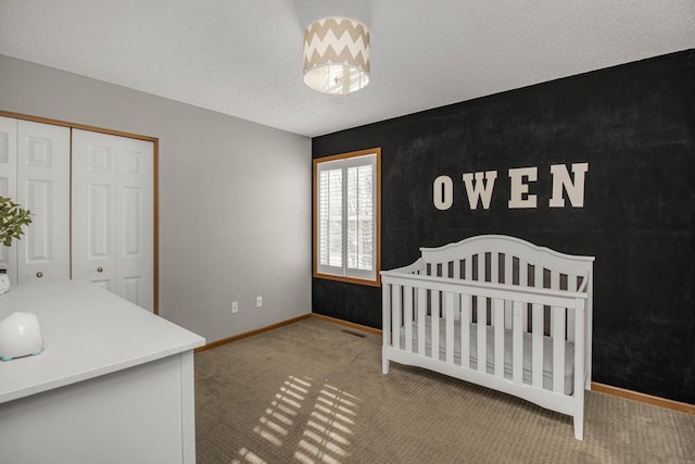 bedroom featuring carpet, a closet, a nursery area, and a textured ceiling