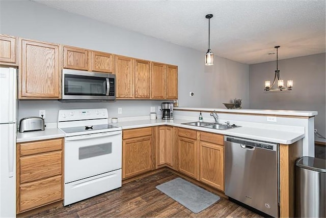 kitchen with appliances with stainless steel finishes, decorative light fixtures, sink, and kitchen peninsula