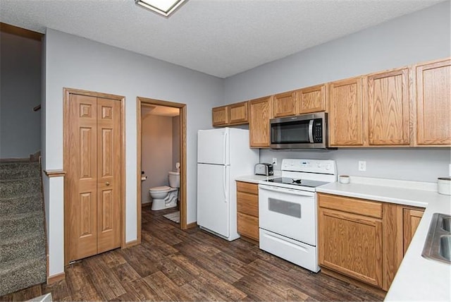 kitchen with white appliances, a textured ceiling, sink, and dark hardwood / wood-style floors