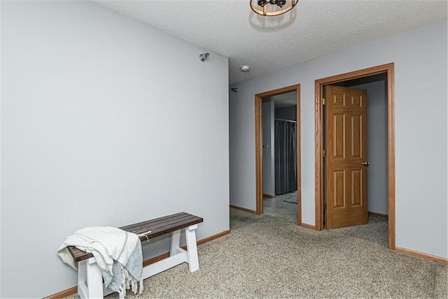 corridor with a textured ceiling and light carpet