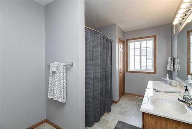 bathroom with a shower with shower curtain, vanity, and a textured ceiling