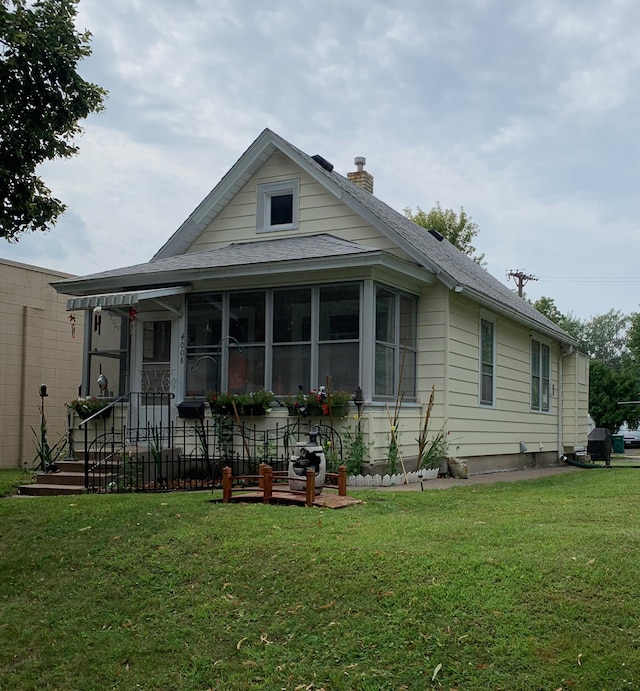 view of front of home featuring a front lawn and a sunroom